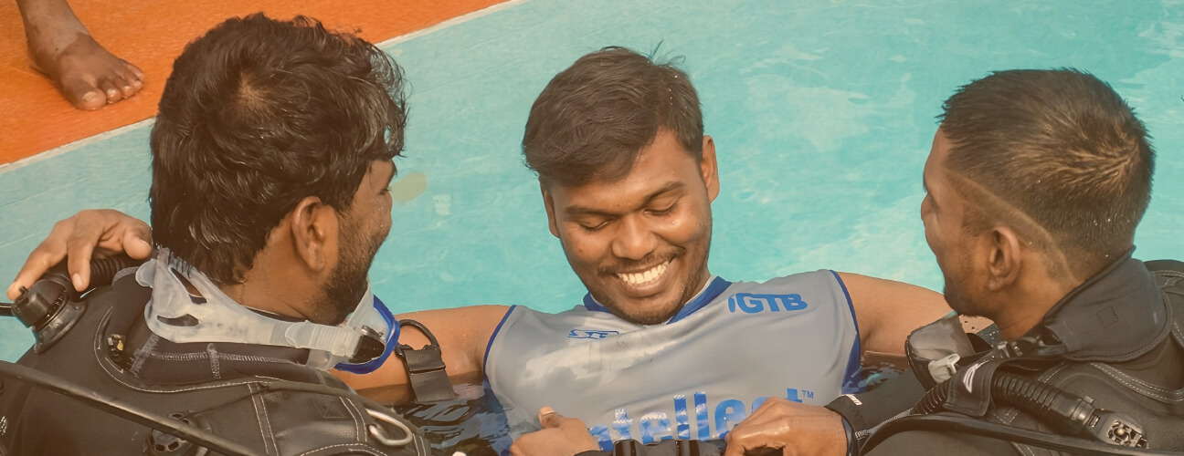 Two volunteers from ABBF conduct an inclusive scuba diving workshop with a person with disability. All three are seen smiling from the experience.